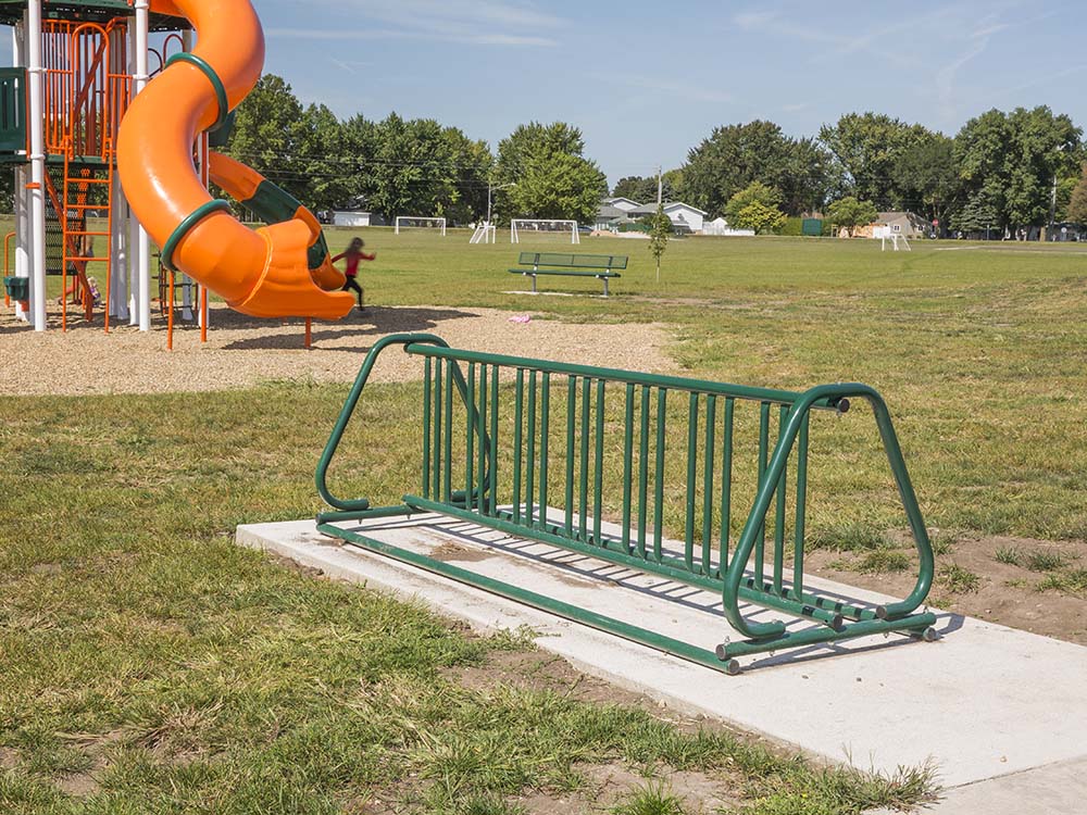 Green bike rack in a park setting.