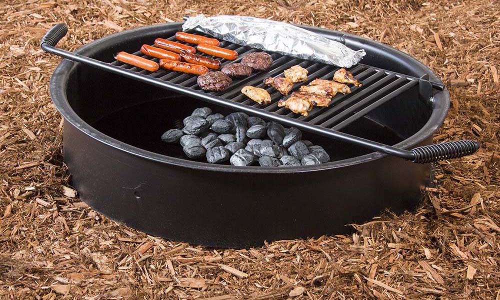 Black portable grill with charcoal and food cooking on it.