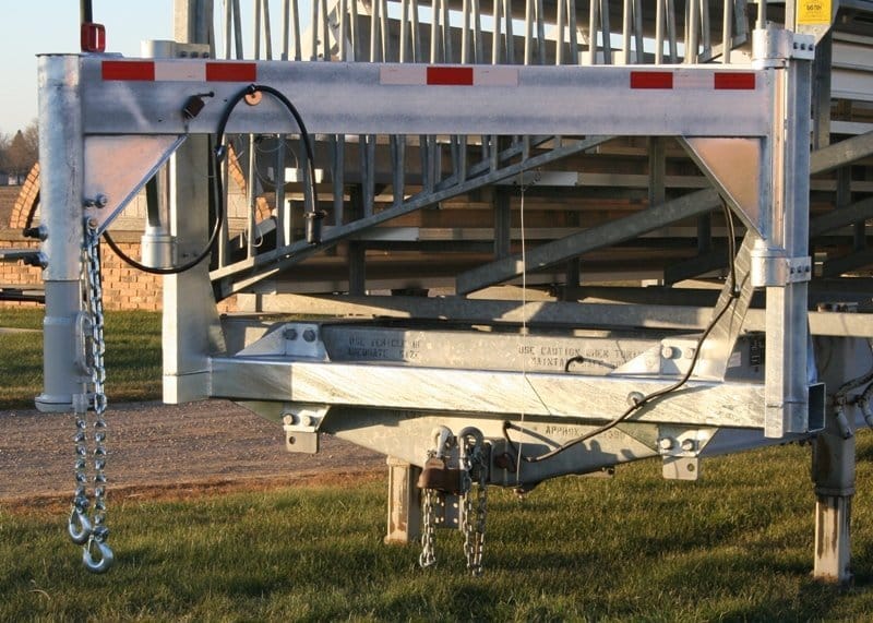 Metal platform with safety rail and chains hanging from it.