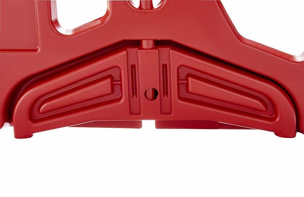 Red plastic object with cut-out shapes and a hole in the center.