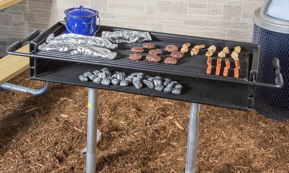 Outdoor grill with charcoal and food cooking on a tabletop.