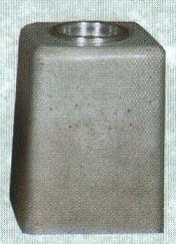 Metallic cylindrical object with a textured surface and circular indentation.