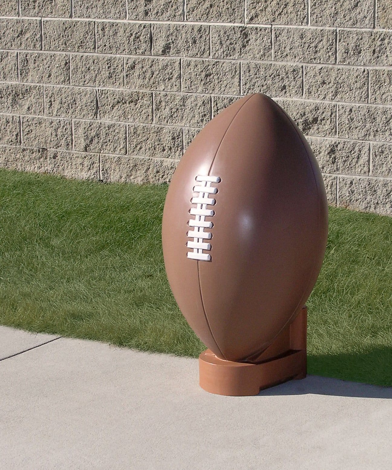 Football on grass against brick wall.