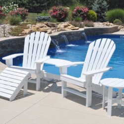 White Adirondack chairs and side table by a pool.