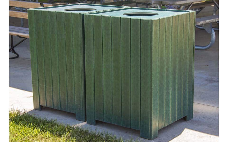 Green outdoor trash can on a patio.