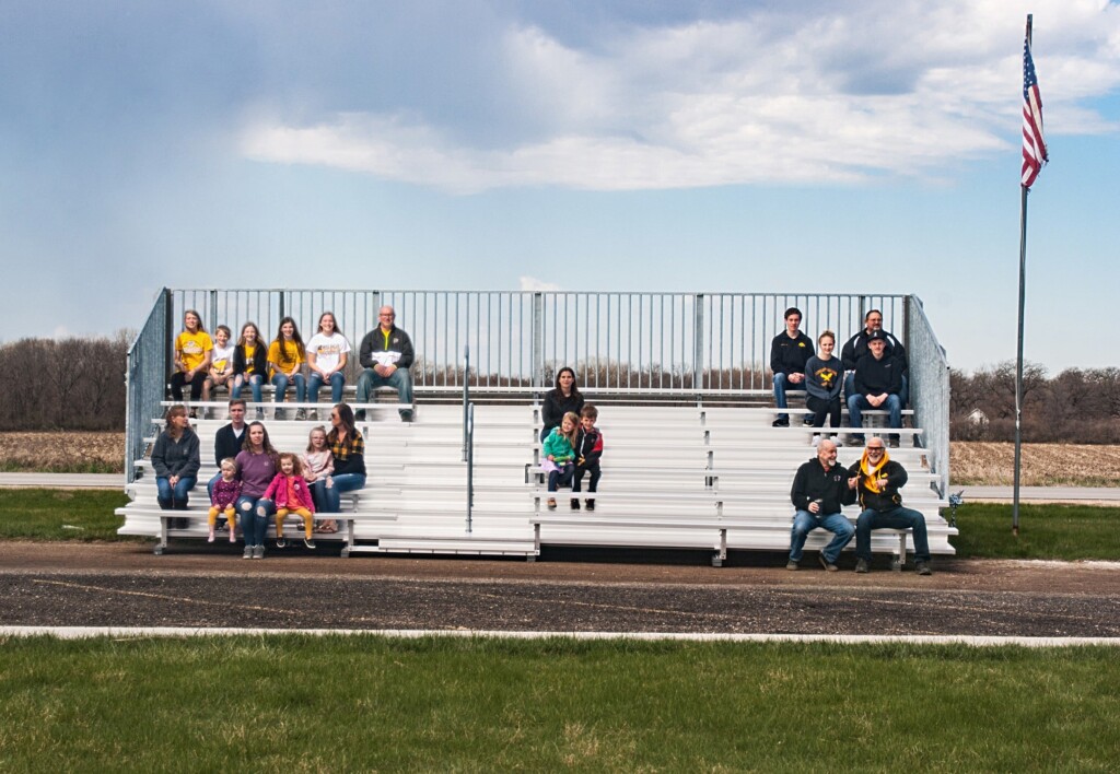 People sitting on bleachers in a field.