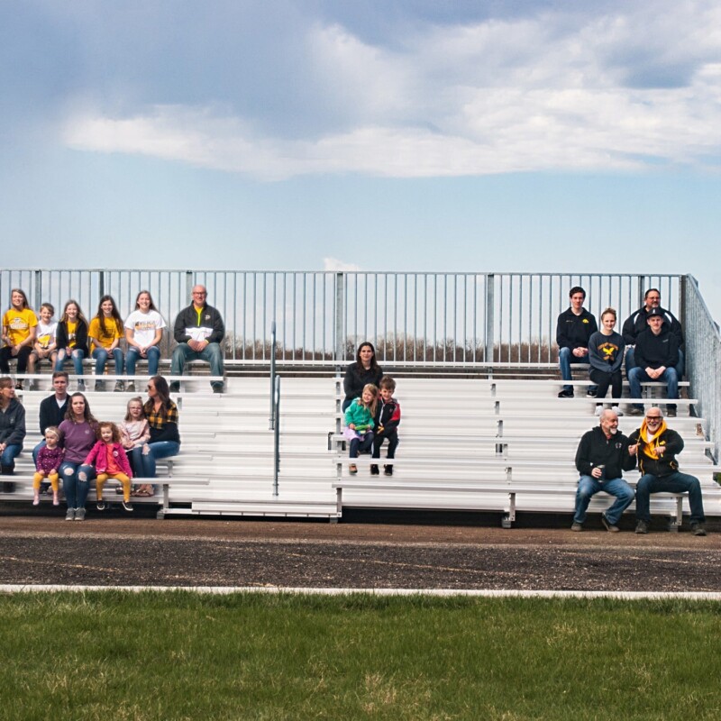People sitting on bleachers in a field.