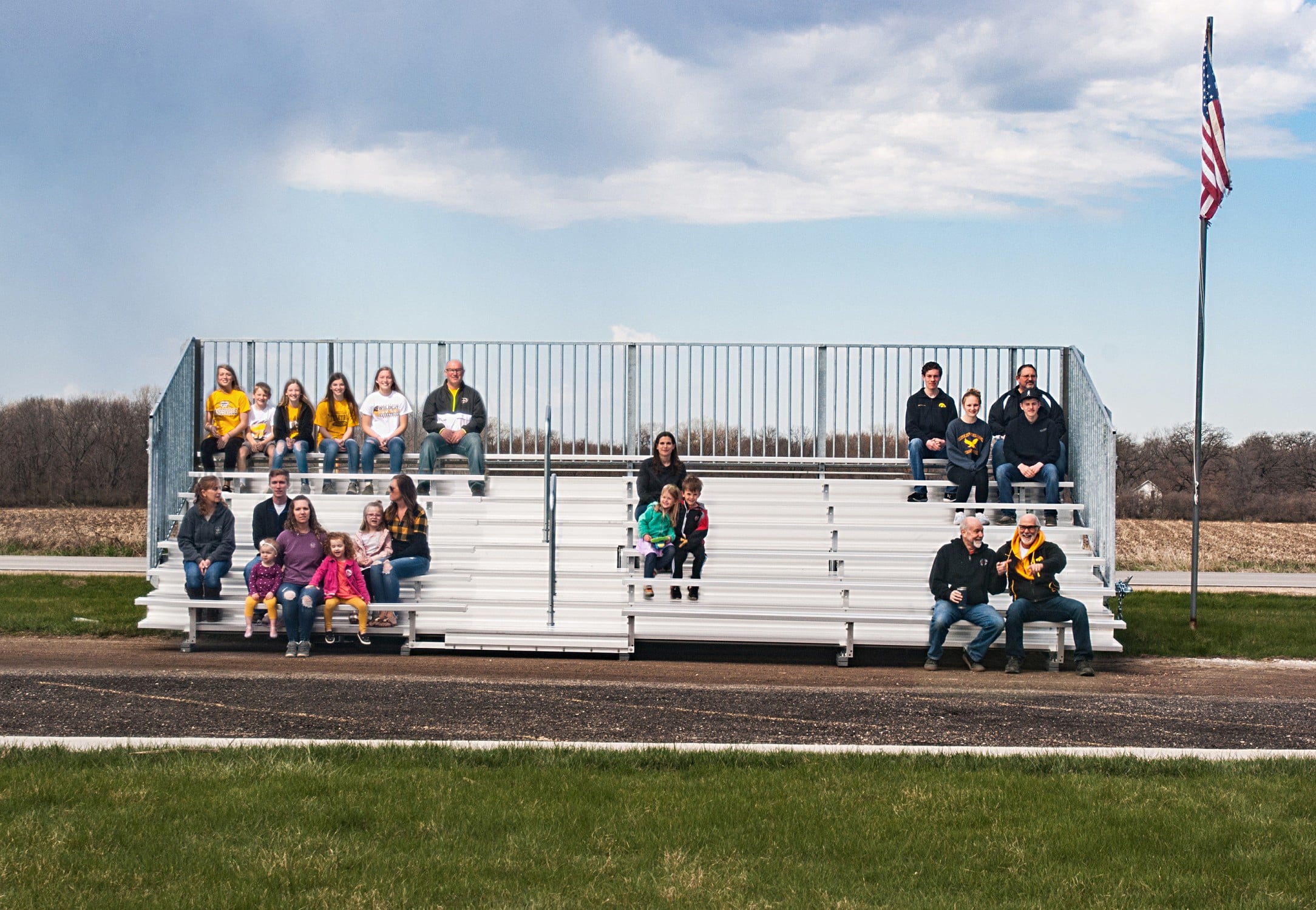 People sitting on bleachers in a field.