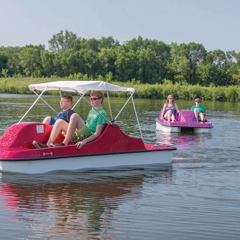 Two people in a red pedal boat on a lake.