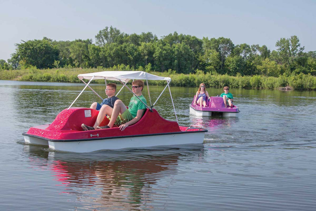 Two people in a red pedal boat on a lake.