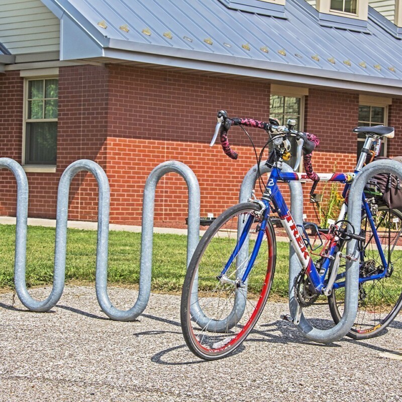 Bicycle parked in a bike rack outside a brick building.