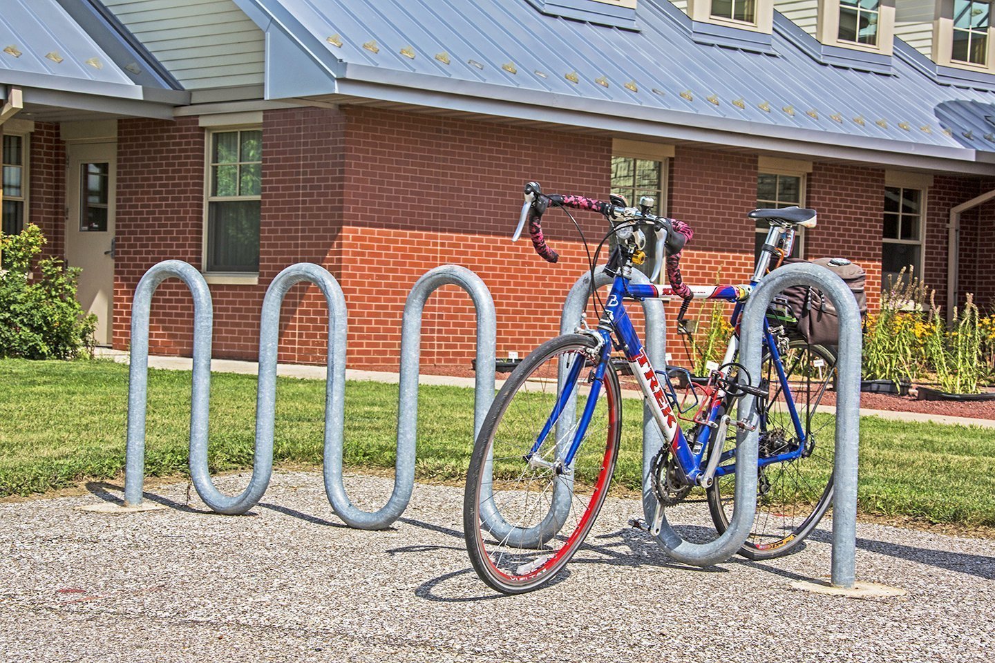 Bicycle parked in a bike rack outside a brick building.
