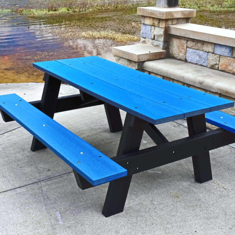 Blue picnic table and benches by a lake.