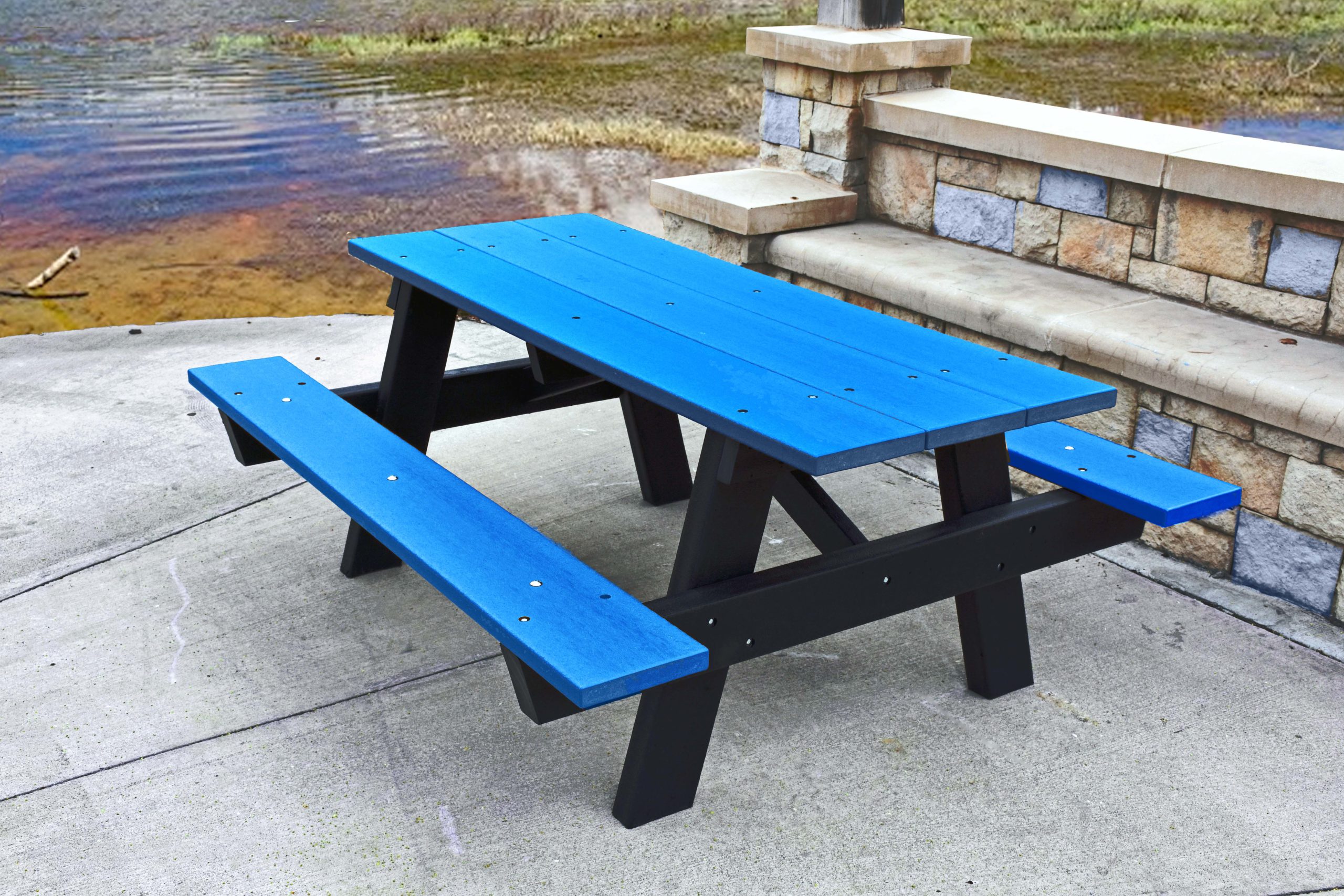 Blue picnic table and benches by a lake.