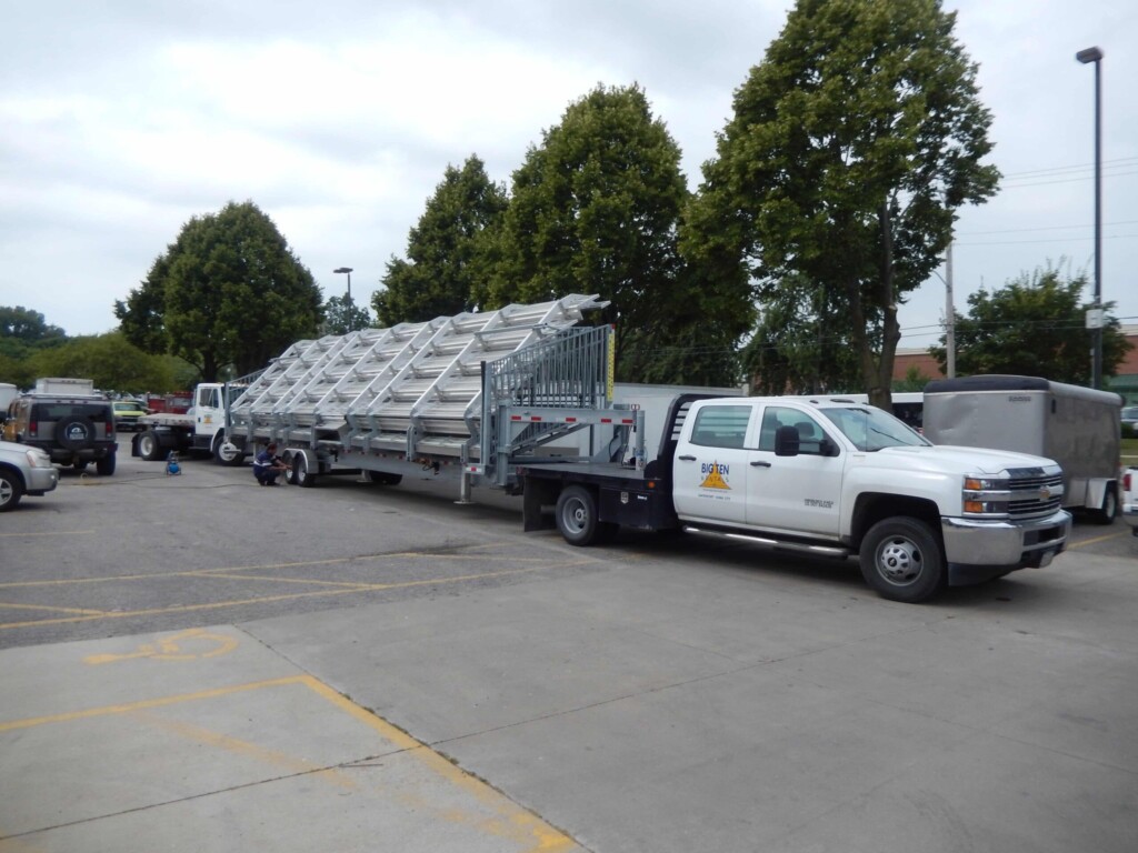 White truck carrying a ladder in a parking lot.