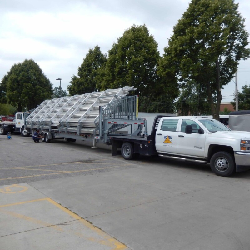 White truck carrying a ladder in a parking lot.
