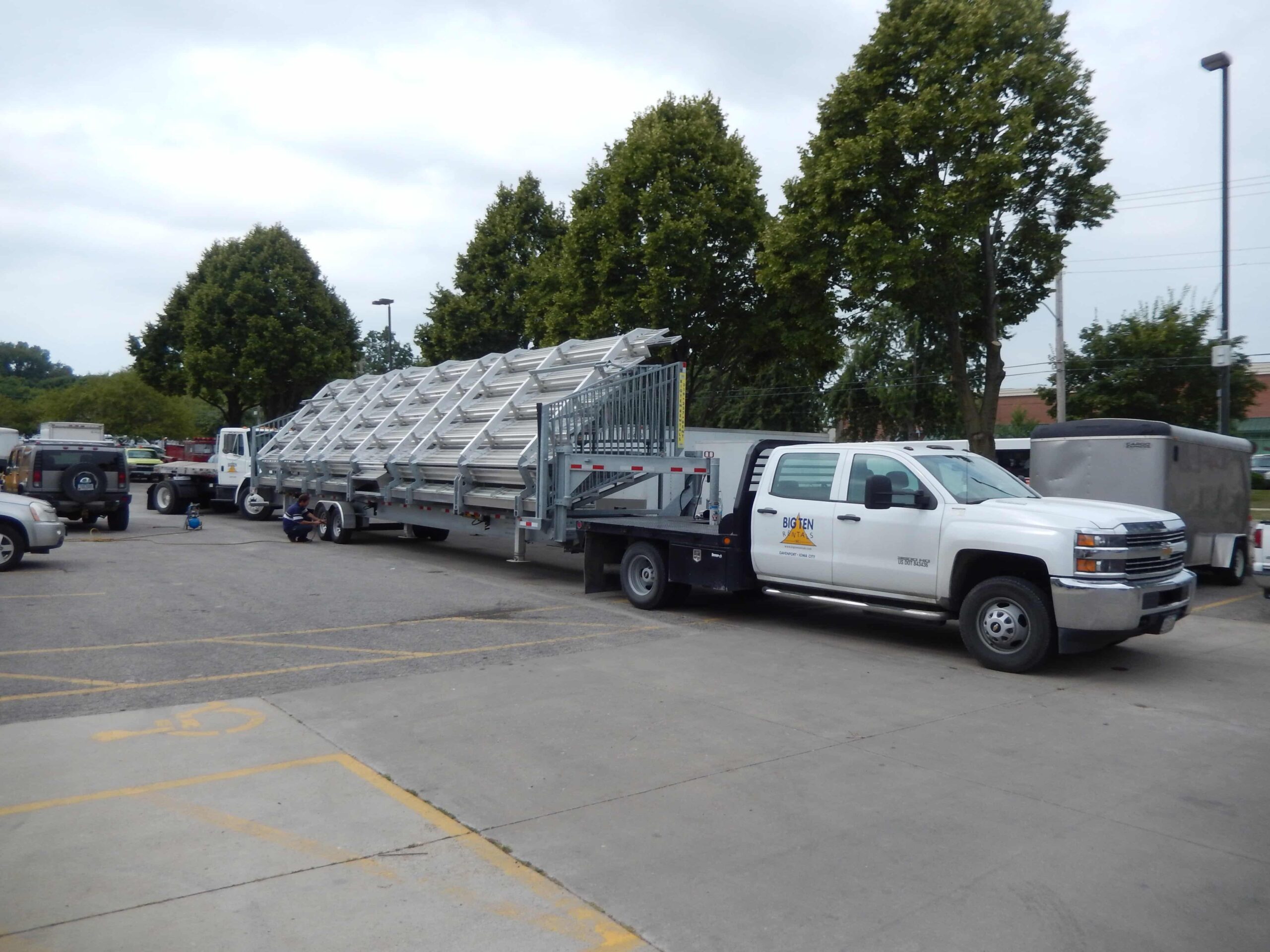 White truck carrying a ladder in a parking lot.