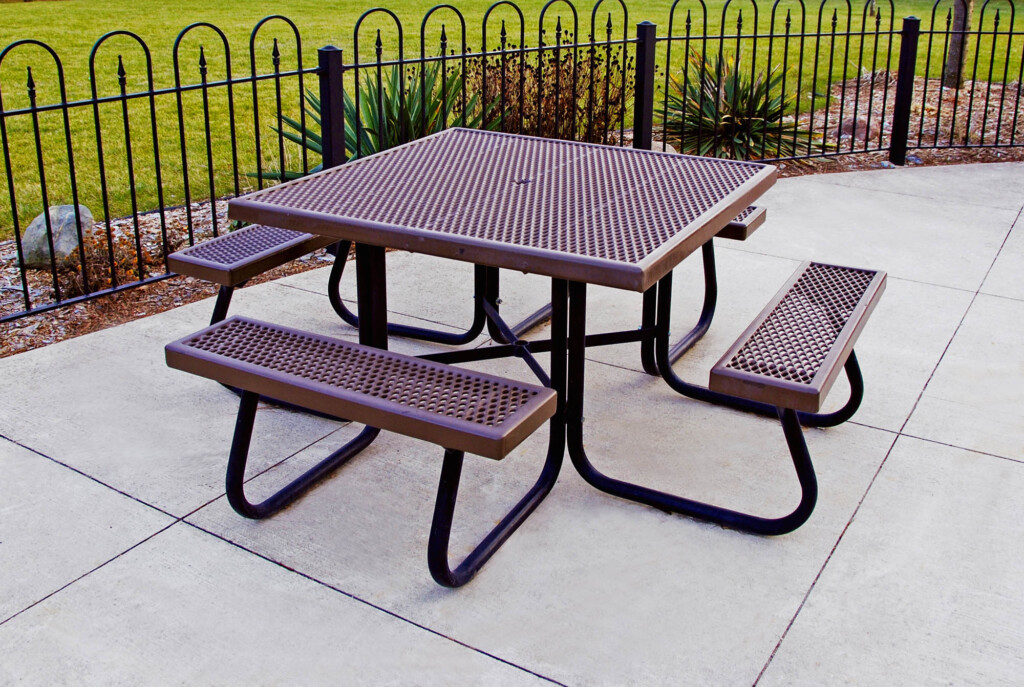 Outdoor picnic table with perforated metal top and benches.