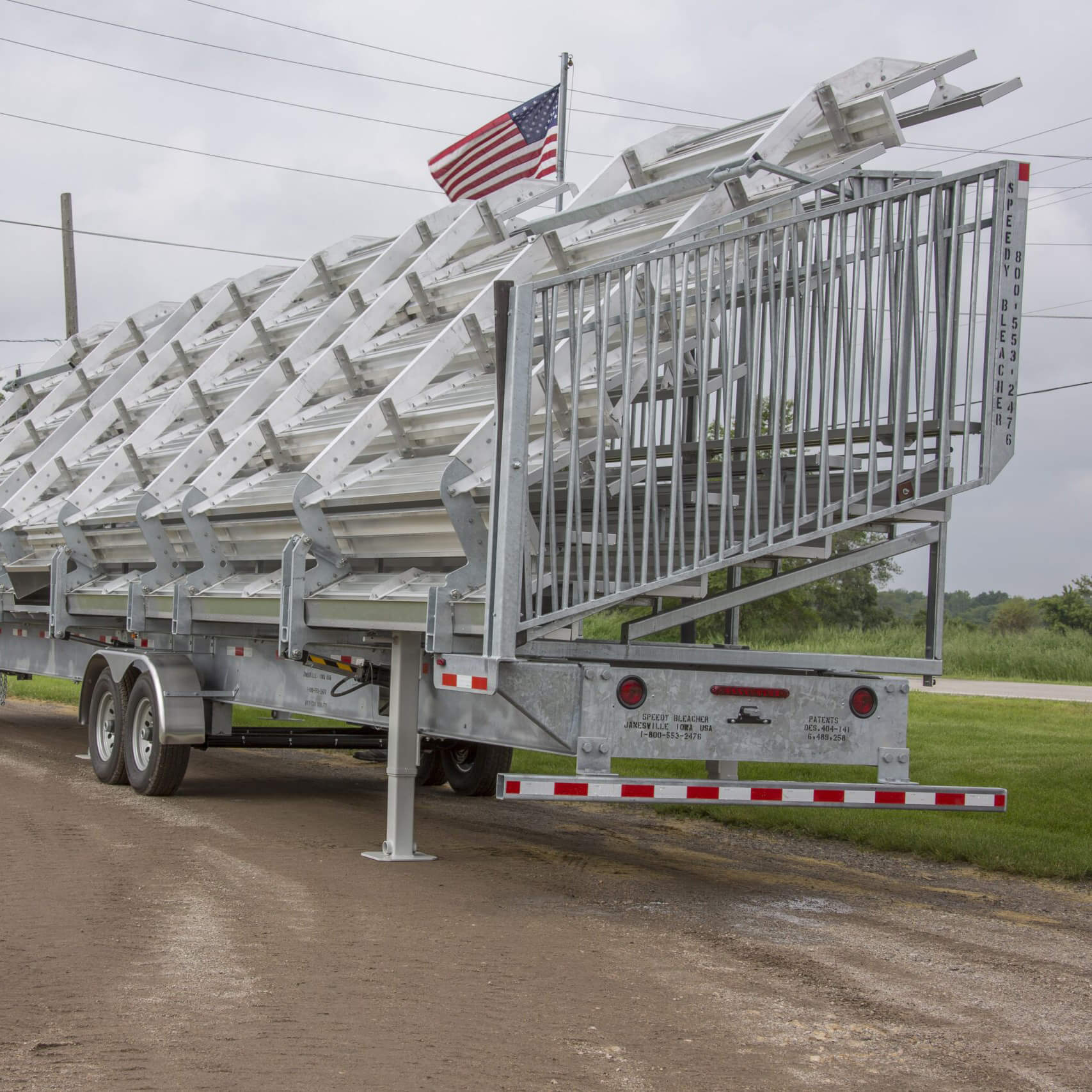 4510F448AHR2WC003_1-scaled Trailer carrying a stack of metal ladders on a dirt road.